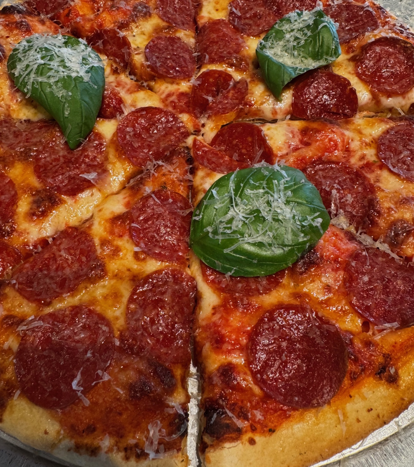 Close-up of a pepperoni pizza with fresh basil leaves and grated parmesan